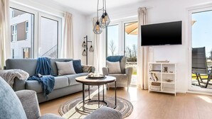 A modern living room with a grey sofa, a round coffee table, and a TV mounted on the wall.