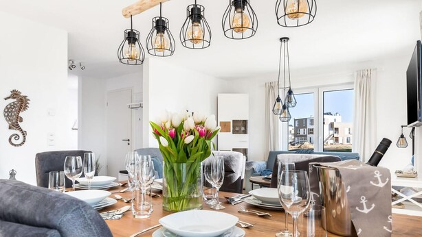 A dining area with a wooden table set for a meal, surrounded by modern furniture.