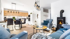 A modern living room with a fireplace, a dining area, and a kitchen with wooden cabinets.