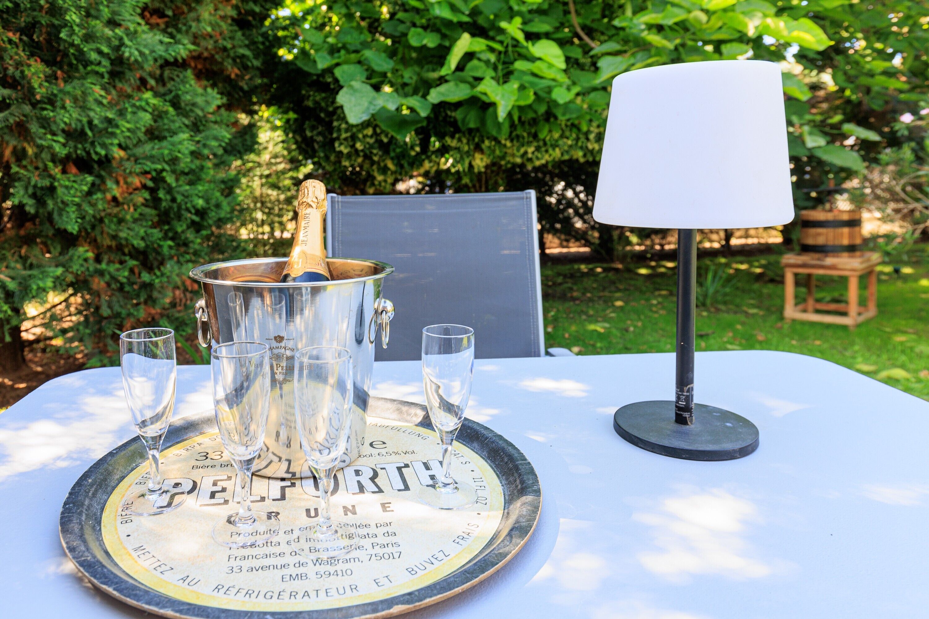 A table with a champagne bottle, glasses, and a tray with text.