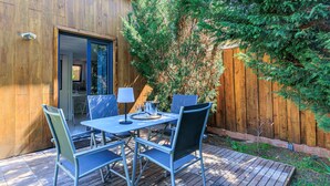 Een terras buiten met een tafel en stoelen, een houten terras en een houten omheining.