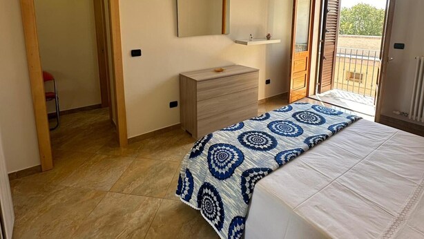 A bedroom with a bed, a dresser, a mirror, and a balcony. - Holiday Home 'Da Katia' with Private Terrace, Balcony and Air Conditioning (Arnesano)