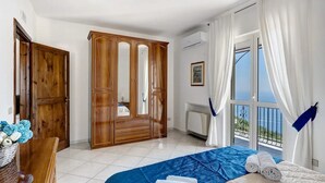 A bedroom with a bed, a wardrobe, a window with a view, and a balcony. - Villa 'Azzurra' with Sea View, Wi-Fi and Air Conditioning (Massa Lubrense)
