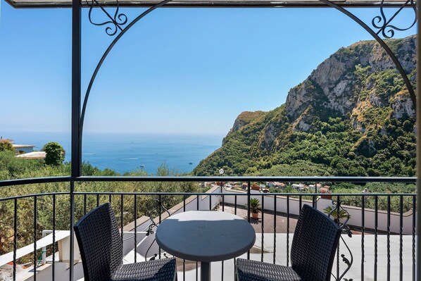 A balcony with two chairs and a table, overlooking a coastal landscape with a clear view of the sea and a mountainous backdrop. - Villa 'Azzurra' with Sea View, Wi-Fi and Air Conditioning (Massa Lubrense)