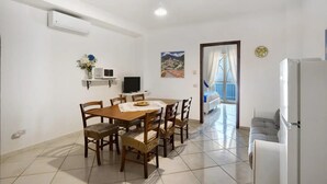 A dining area with a table and chairs, a TV, and a balcony with a view. - Villa 'Azzurra' with Sea View, Wi-Fi and Air Conditioning (Massa Lubrense)