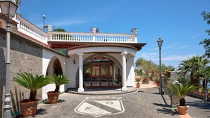 A building with a white facade, arched entrance, and a balcony with potted plants. - Villa 'Azzurra' with Sea View, Wi-Fi and Air Conditioning (Massa Lubrense)