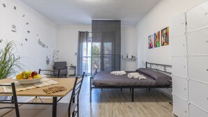 Una habitación moderna con cama, una mesa de comedor con sillas, un escritorio pequeño y una ventana con cortinas.