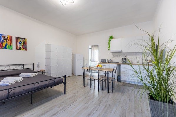 A modern room with a bed, a dining table, and a kitchen area.