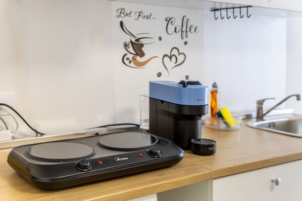 A kitchen with a coffee maker, a kettle, and a coffee-themed wall art.