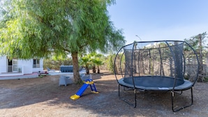 A backyard with a trampoline, a slide, and a tree. - Apartment 'Trilocale In Villa Con Piscina' with Mountain View, Shared Pool and Wi-Fi (Comiso)