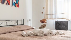 A neatly made bed with rolled towels, a black metal headboard, and a wall with abstract art. - Apartment 'Trilocale In Villa Con Piscina' with Mountain View, Shared Pool and Wi-Fi (Comiso)