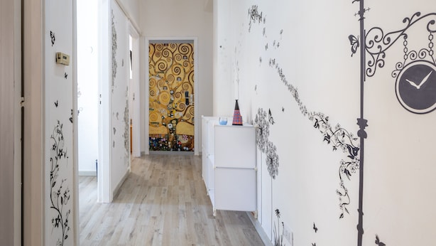 A hallway with a patterned wall, a clock, and a door leading to another room. - Apartment 'Trilocale In Villa Con Piscina' with Mountain View, Shared Pool and Wi-Fi (Comiso)