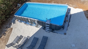 A rectangular swimming pool with a ladder, surrounded by a gravel area and four lounge chairs. - Apartment 'Trilocale In Villa Con Piscina' with Mountain View, Shared Pool and Wi-Fi (Comiso)