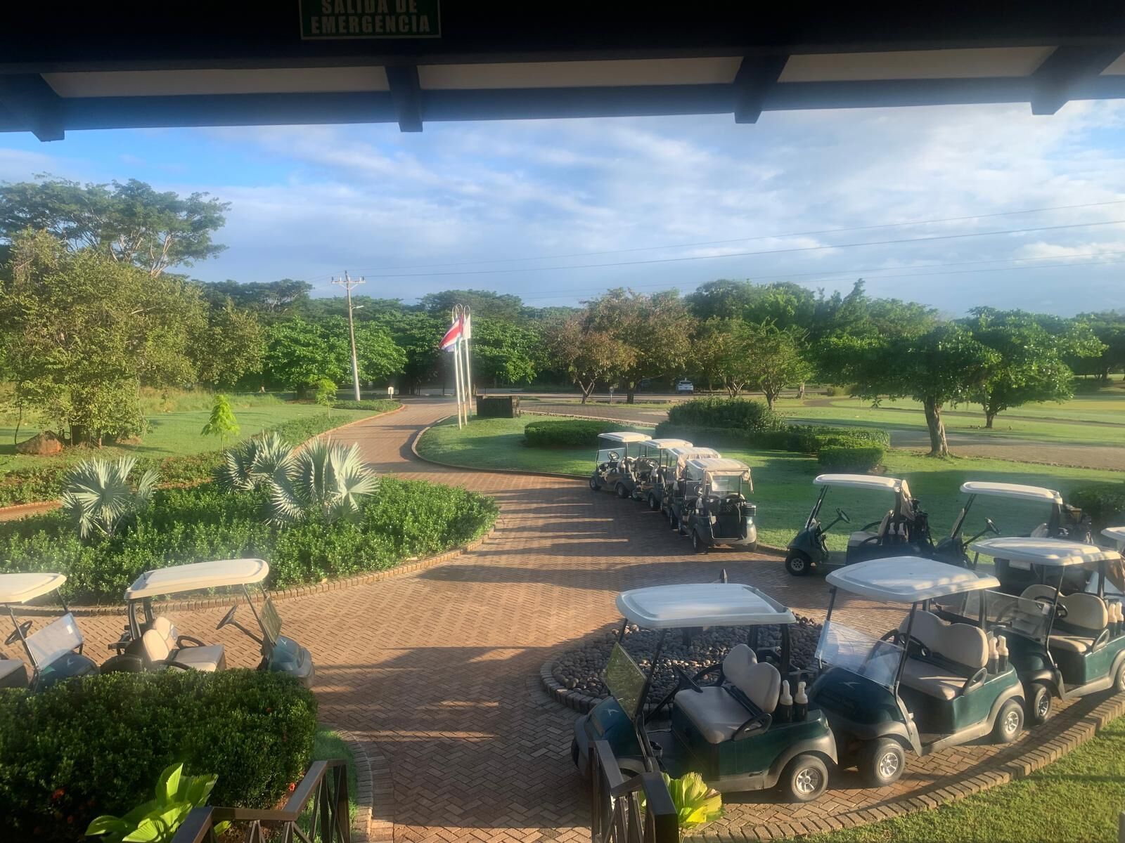 A golf course with a covered area and a sign reading "SALIDA DE EMERGENCIA".