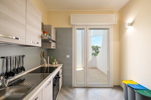 A modern kitchen with a built-in oven, a sink, and a window overlooking a balcony. - Apartment 'i Portici Unità 101' with Balcony and Wi-Fi (san pietro in bevagna)