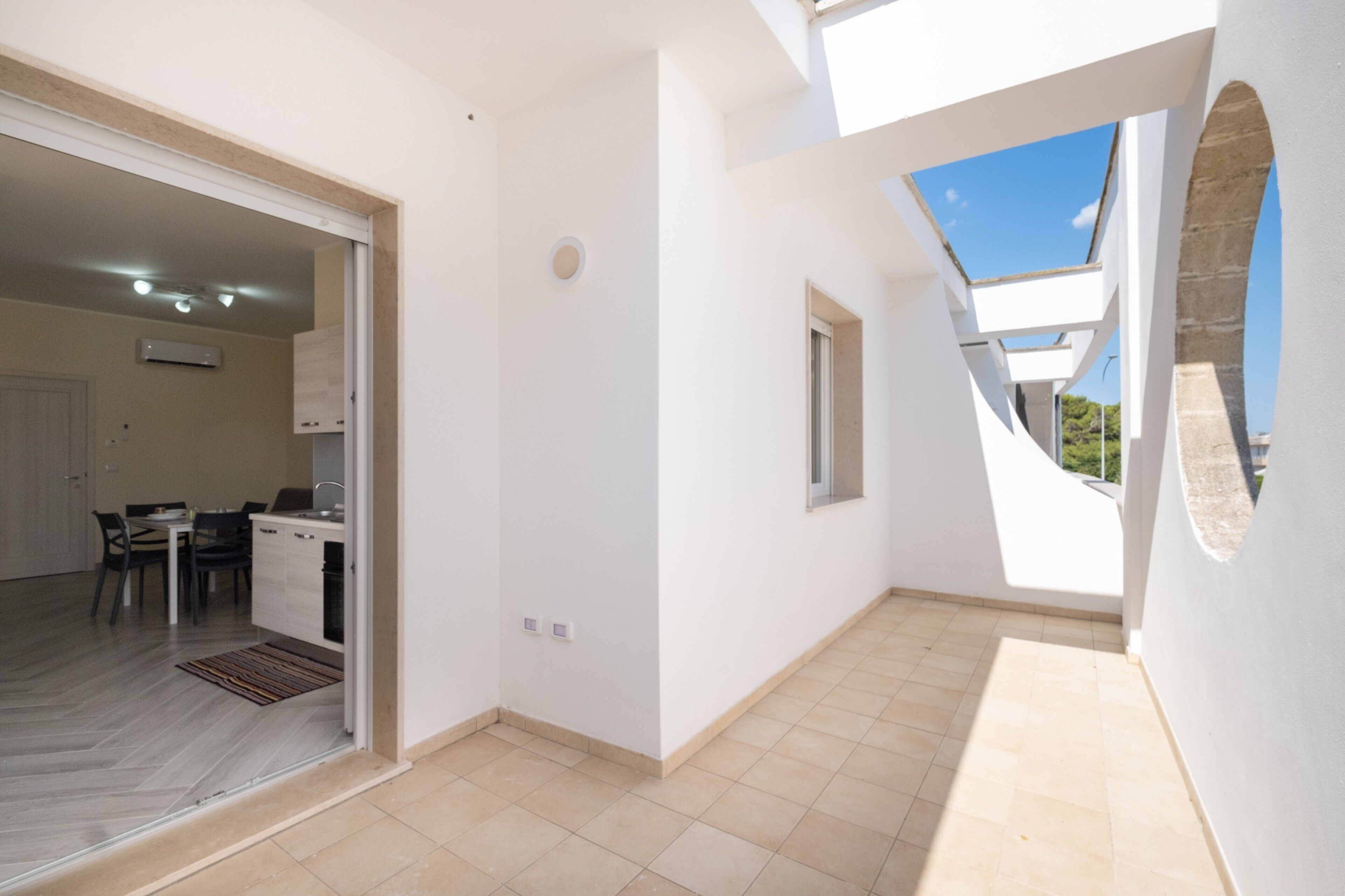 Une vue intérieure d’un appartement moderne comprenant une cuisine, un coin repas et un balcon avec vue.