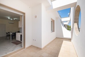 An interior view of a modern apartment with a kitchen, dining area, and a balcony with a view. - Apartment 'i Portici Unità 101' with Balcony and Wi-Fi (san pietro in bevagna)
