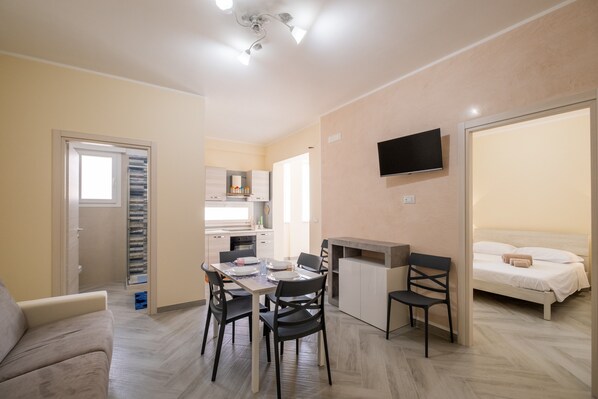 A compact living space with a dining area, kitchenette, and a bed.