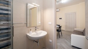 Un baño moderno con lavamanos, espejo y ducha.