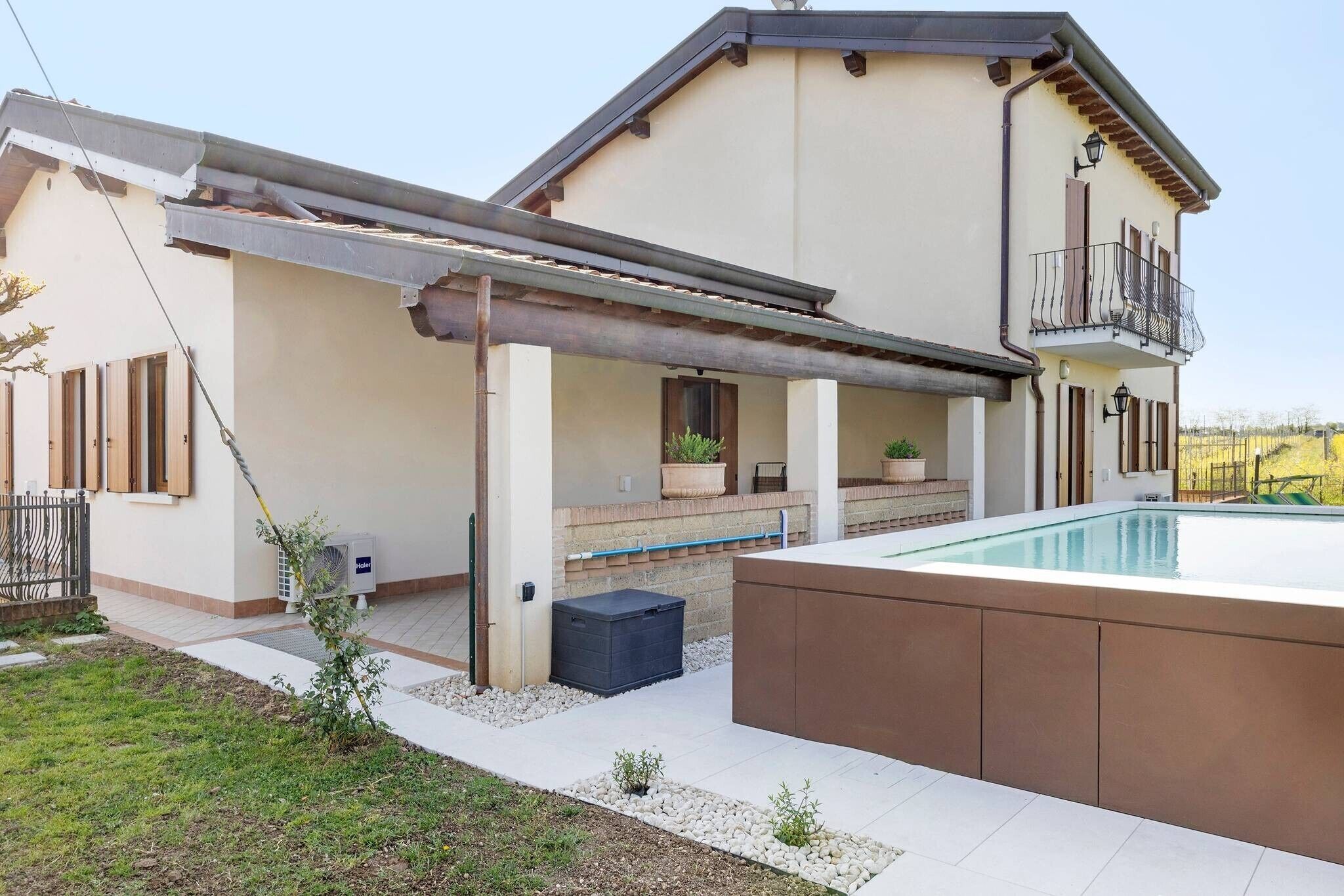 Een modern huis met een overdekte patio, een zwembad en een balkon.