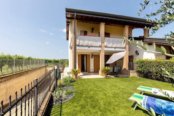 A two-story building with a balcony, a well-maintained lawn, and a fence.