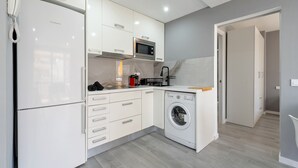 A compact kitchen with a refrigerator, microwave, oven, and washing machine. - Calafenga Apartment with Sea Views, Wi-Fi, and Air Conditioning (Calafell)