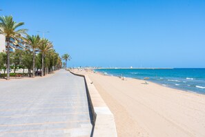 A beach with a paved walkway lined with palm trees, leading to the ocean. - Apartment 'Calafenga' with Spacious Balcony with Sea View, Parking, Wi-Fi and Air Conditioning (Calafell)