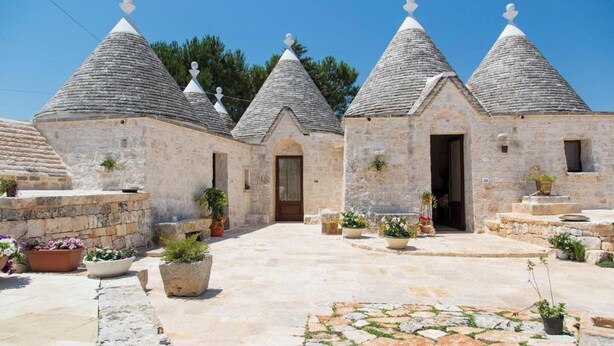 Un patio con edificios de piedra, cada uno con techo cónico y una puerta pequeña.