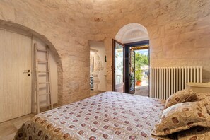 A bedroom with a bed, a wooden wardrobe, a ladder, an arched doorway, and a radiator. - Null 'La Rondine' with Shared Terrace, Shared Garden and Wi-Fi (Locorotondo)