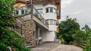 Ein modernes, mehrgeschossiges Gebäude mit Steinverkleidung, einem Balkon und einem Auto auf der Auffahrt.