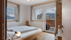 Ein Schlafzimmer mit Bett, Schreibtisch, Stuhl und Blick ins Freie.