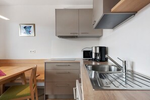 Une cuisine moderne équipée d’un four à micro-ondes encastré, d’une machine à café et d’un évier en acier inoxydable.