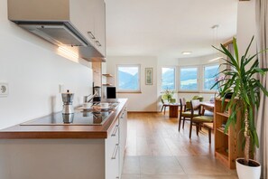 Une cuisine moderne dotée d’un îlot central, de planchers en bois et offrant une vue sur les montagnes grâce à de grandes fenêtres.