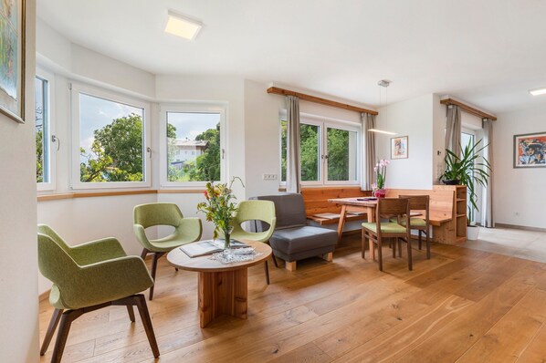 Un salón moderno con comedor, ventanas amplias y vistas a zonas verdes.