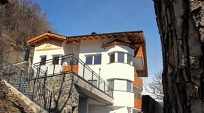 Un edificio de varios pisos con una escalera de piedra, balcones y un cielo despejado.