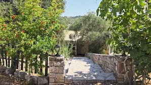 Un chemin de pierre mène à un bâtiment doté d’un mur en pierre rustique et d’un portail en métal.