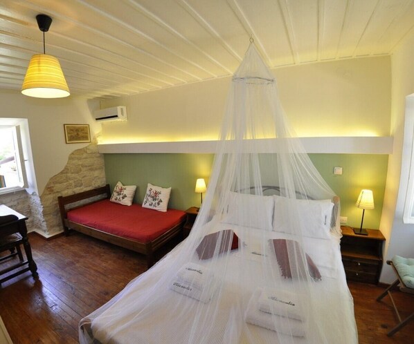 Un dormitorio con cama con dosel, un escritorio, una silla, una lámpara y un ventanal.
