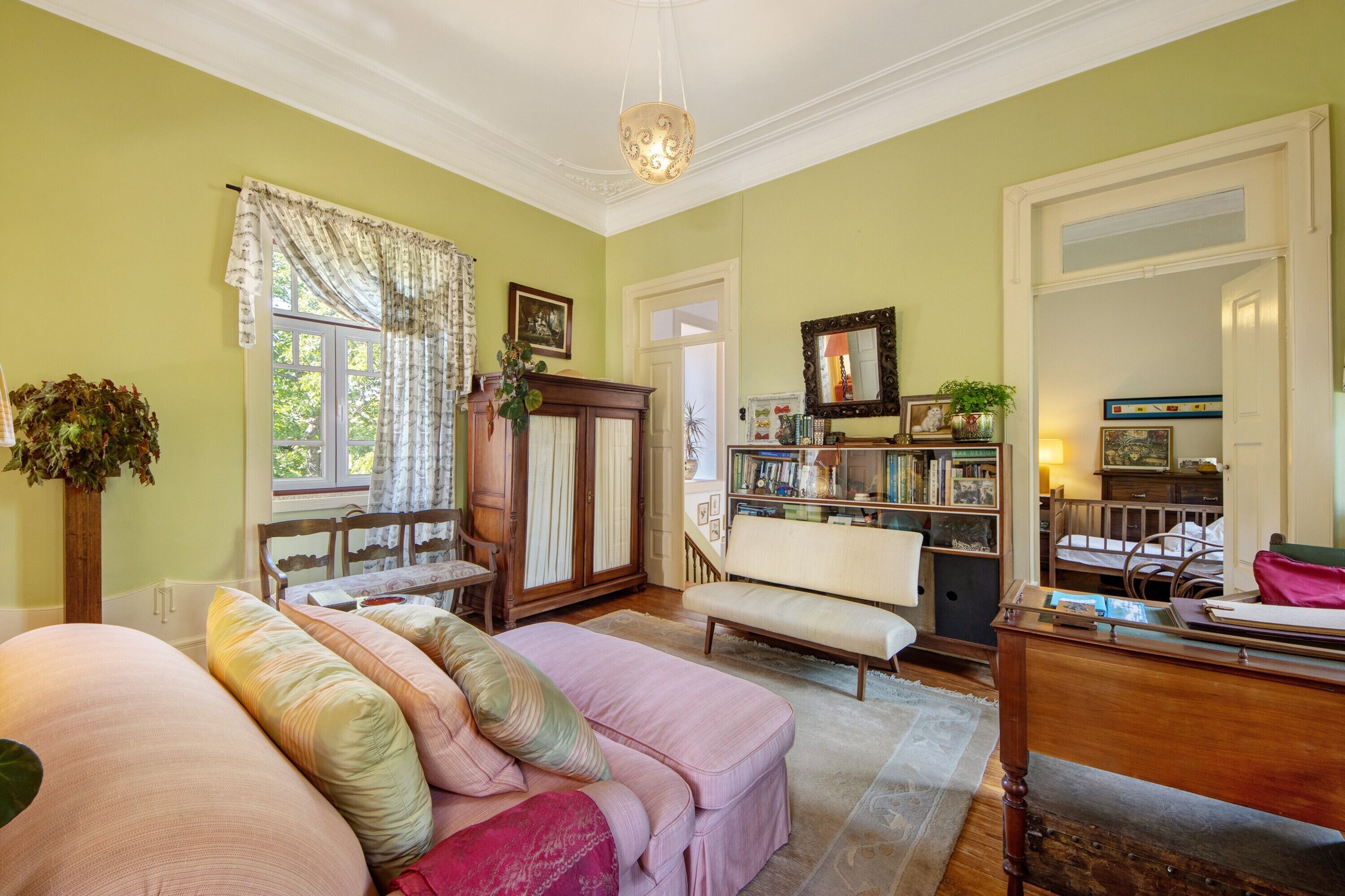 A room with a sofa, a wooden chair, a bookshelf, and a desk.