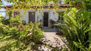 A house with a tiled roof, a front door, and a garden with various plants and a pathway leading to the entrance.