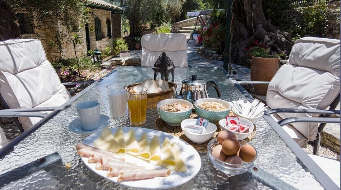 Une table dressée à l’extérieur, avec de la nourriture et des boissons, entourée de chaises.