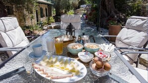 A table set outdoors with food and drinks, surrounded by chairs.