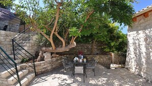 A stone patio with a table and chairs, a tree, and a staircase.