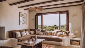 Una sala de estar con un sofá seccional, una mesa de centro de madera y un ventanal con vistas a zonas verdes.