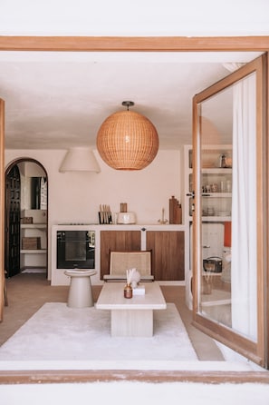 A modern kitchen with a built-in oven, a dining table, and a hanging light fixture.