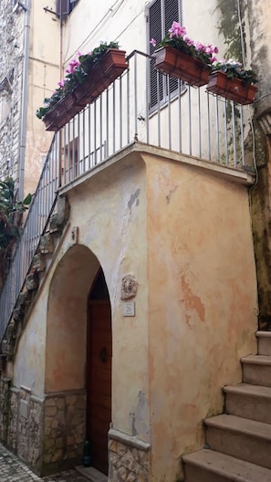 A building with a stone base, a wooden door, and a metal railing with flower boxes. - Apartment 'Appartamento Luxury -  Mare' with Sea View and Air Conditioning (Terracina)
