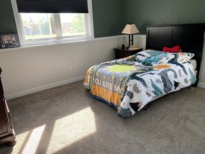 A bedroom with a bed, a nightstand, a lamp, and a window.