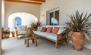 A sunlit living room with a sofa, coffee table, and potted plants. - Villa 'Xenofilia 6' with Sea View, Wi-Fi and Air Conditioning (Benitachell)