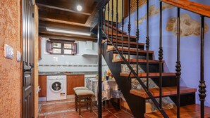 A kitchen with a washing machine, a dining table with chairs, and a staircase with wooden steps and black balusters. - Country House 'El Llosín' with Private Terrace, Balcony and Wi-Fi (Ribadesella)