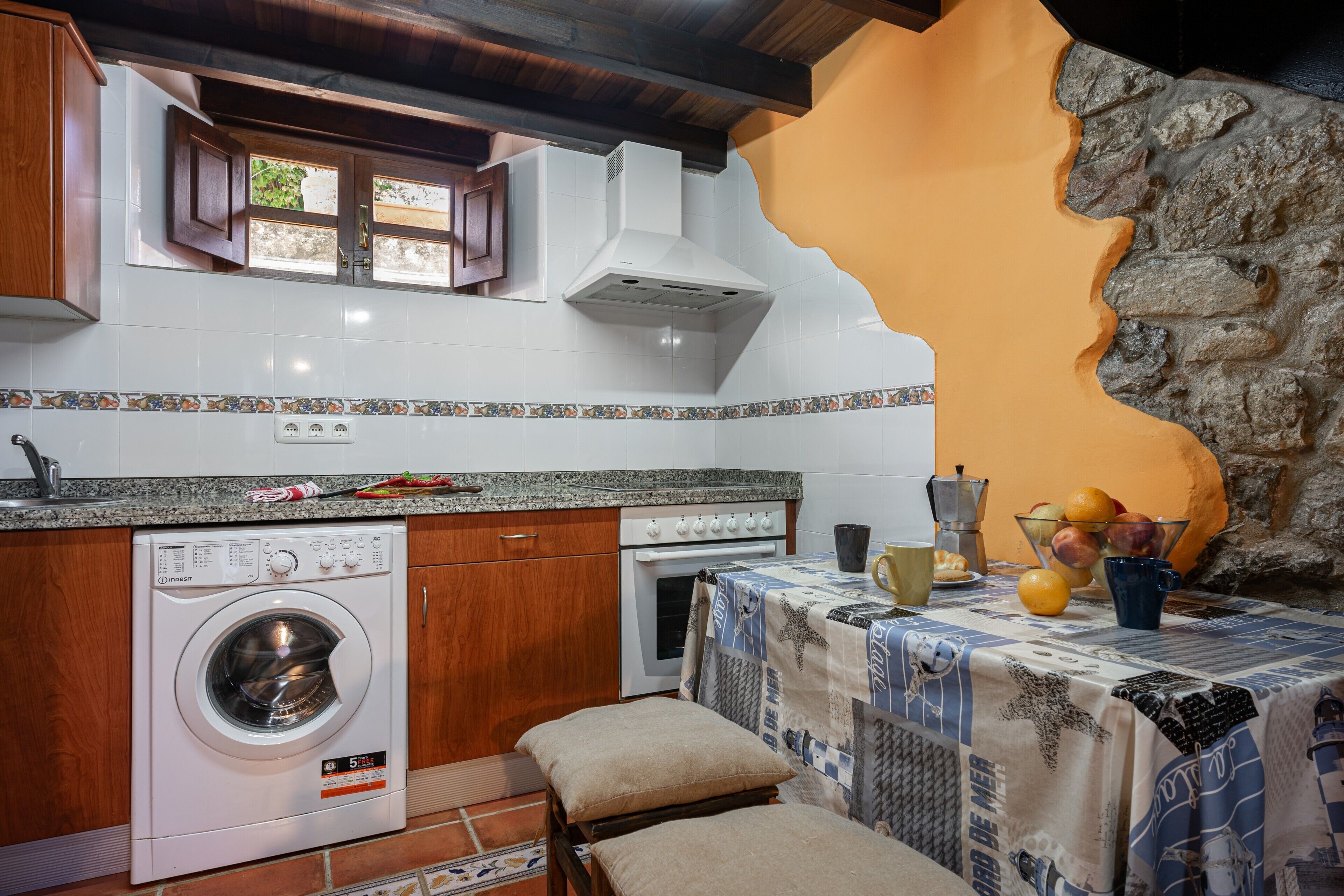 Une cuisine compacte équipée d’un lave-linge, d’un four et d’une table recouverte d’une nappe.
