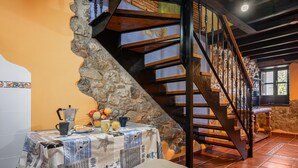 A dining area with a table set for two, a stone staircase, and a window with natural light. - Country House 'El Llosín' with Private Terrace, Balcony and Wi-Fi (Ribadesella)